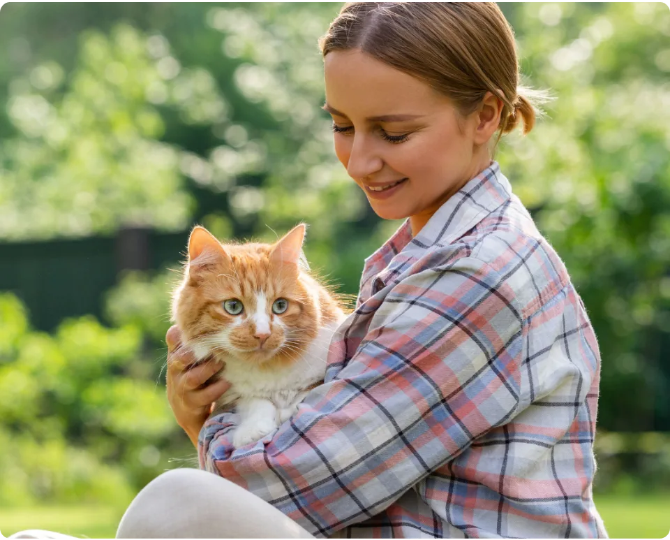 A young woman holding her orange tabby cat